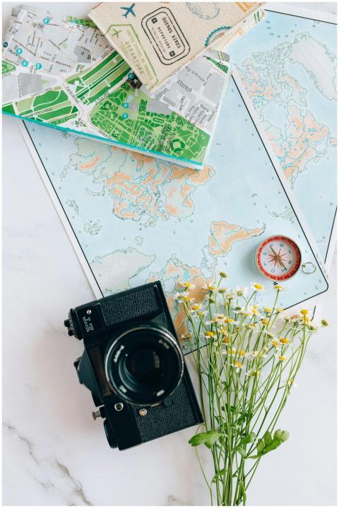 A nostalgic flatlay of a camera, maps, and compass