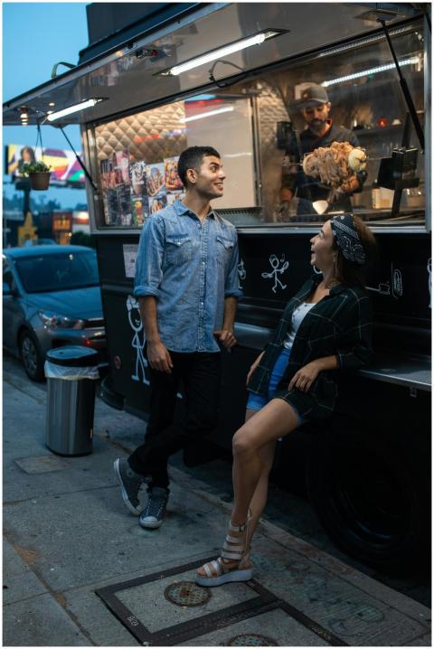 Two friends happily chatting by a food truck, enjo