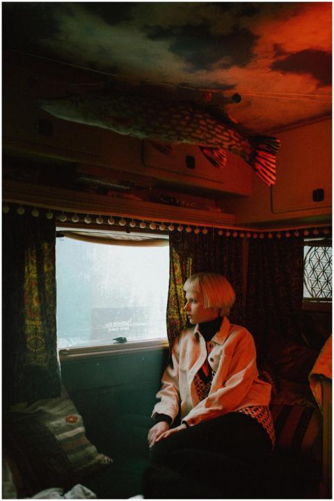 Blonde woman sitting in a vintage van interior, lo