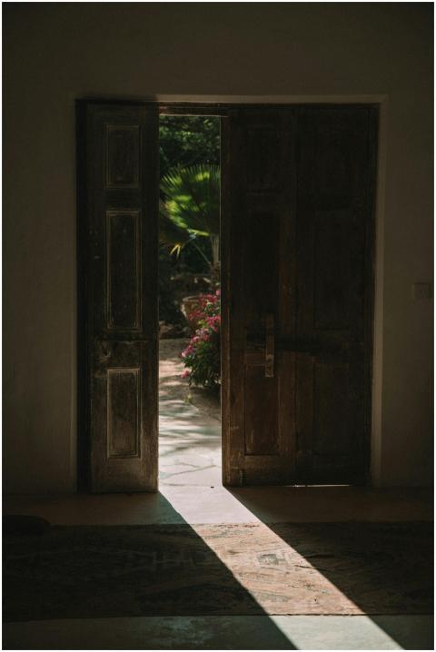 A rustic wooden door opens to reveal a sunlit gard
