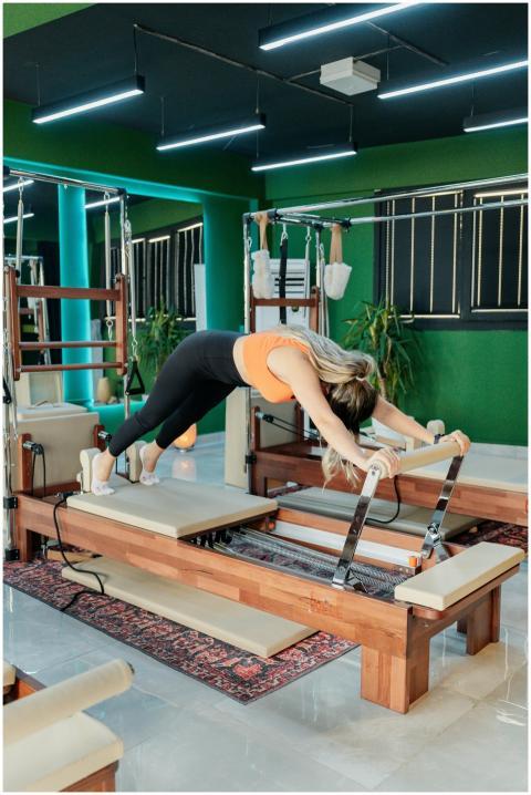 A woman exercises on a Pilates reformer machine in