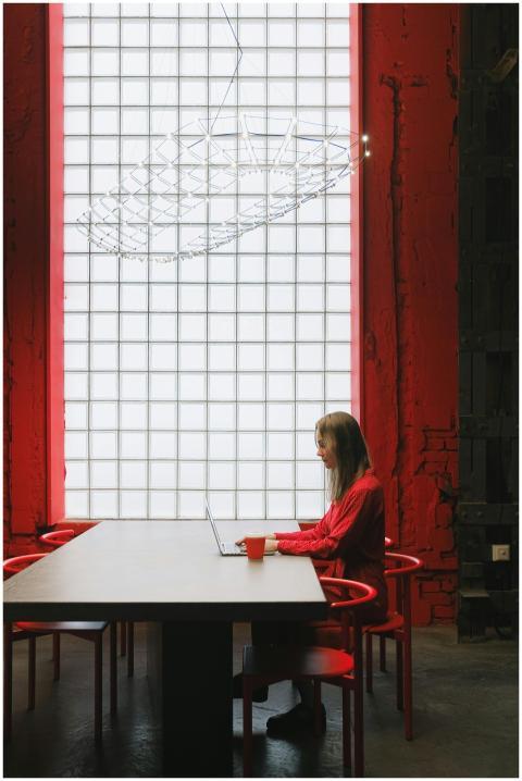 A woman works on a laptop at a red-themed, modern