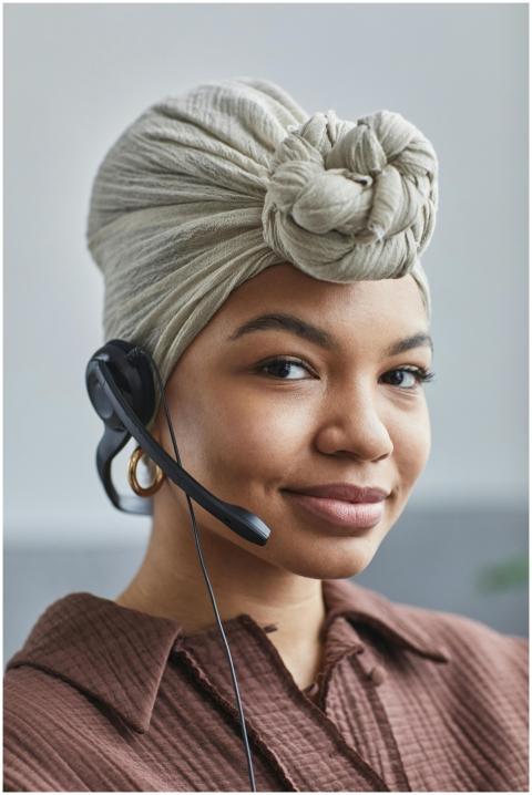 Smiling black woman in a head wrap and headset wor