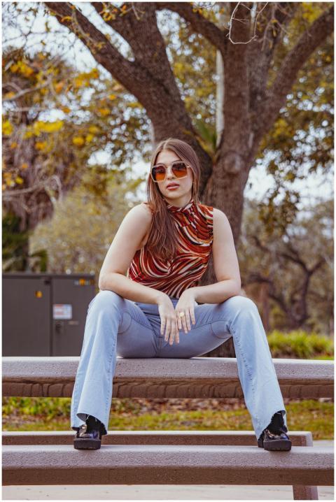 Chic young woman with sunglasses sitting on a park