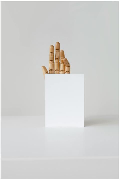 Wooden hand holding a blank card on a neutral back