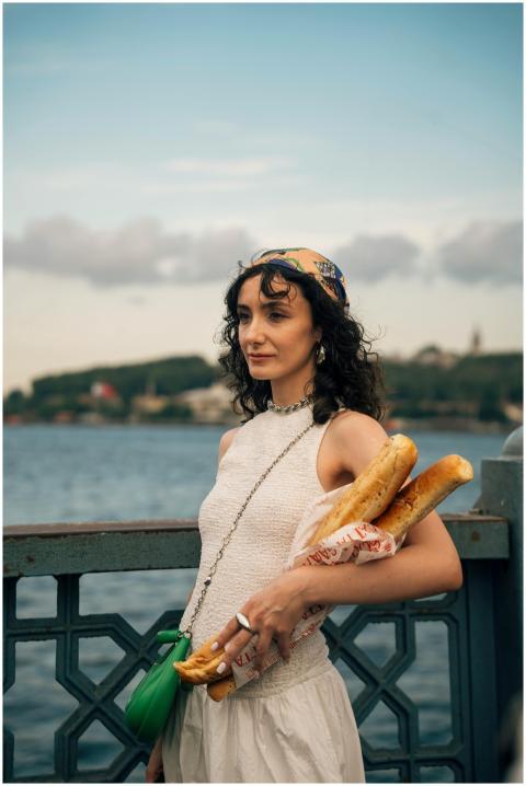 Woman in stylish attire holding baguettes on a riv
