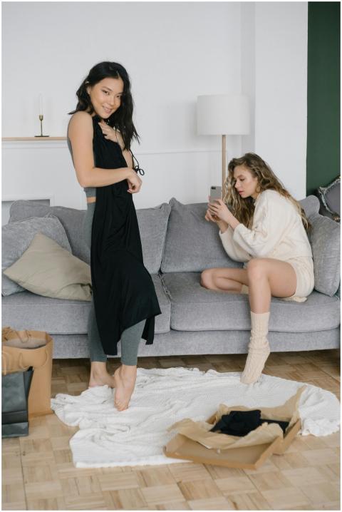 Two women relaxing while trying on new clothing pu