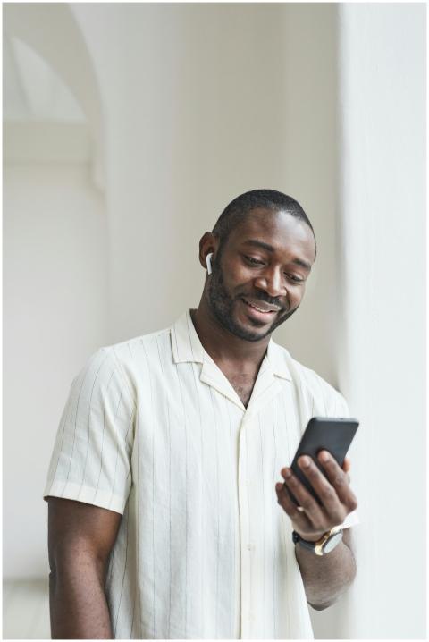 Smiling man wearing earbuds and holding smartphone