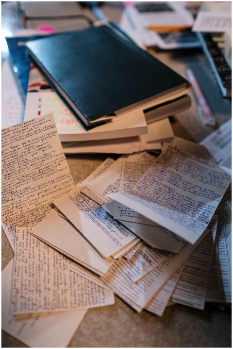 Scattered handwritten notes and books on a desk, p