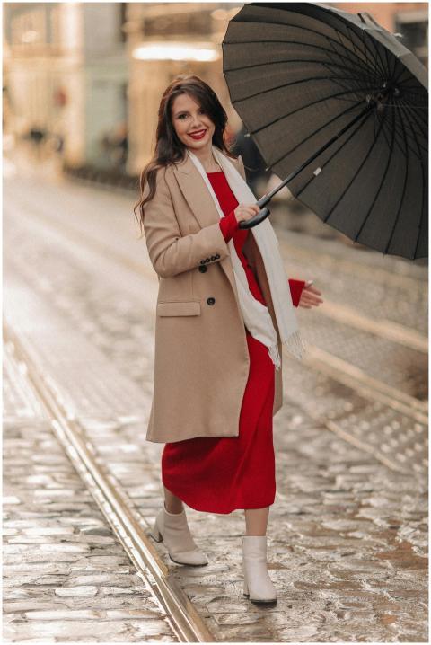 Fashionable woman in a red dress and coat smiles w