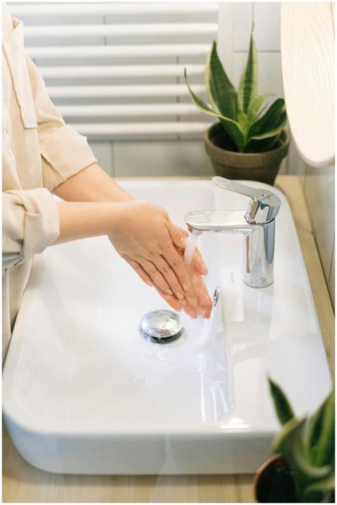 Close-up of hands being washed under a faucet with