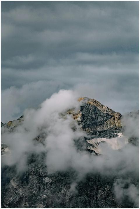 A majestic mountain peak shrouded in clouds, creat