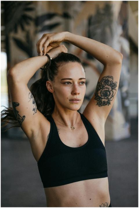 Athletic woman with tattoos tying her hair outdoor