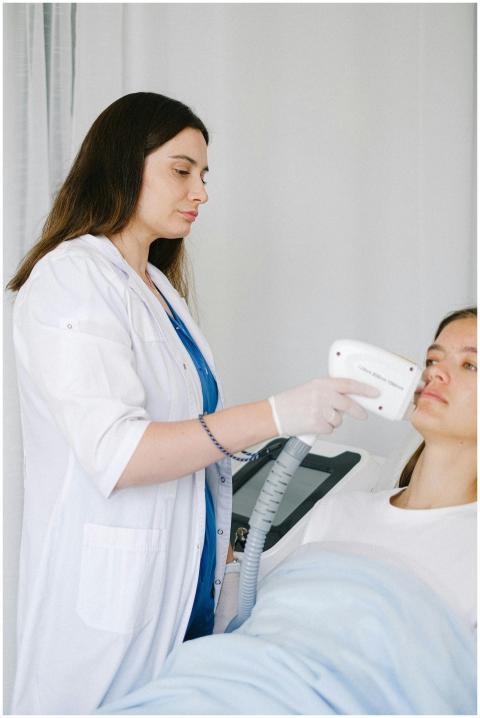 Female specialist performing laser therapy on pati