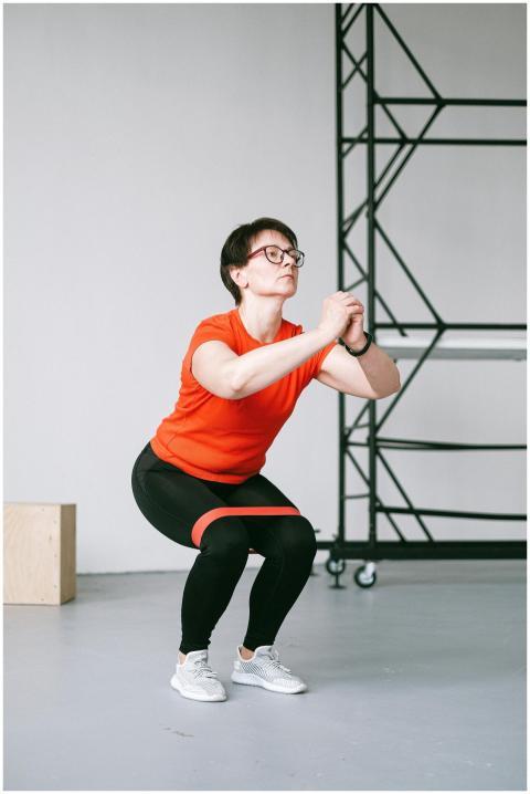 Athletic woman squatting in sportswear with a gray