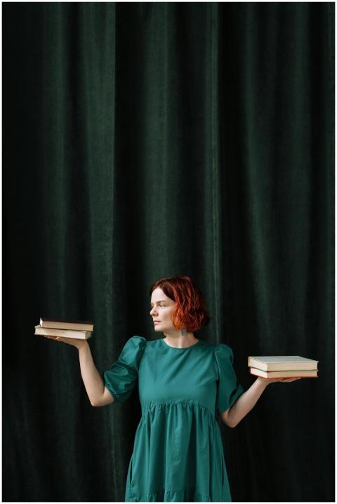 Woman in green dress balancing books with dark cur
