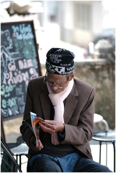 An elderly man reading a magazine in a local cafe