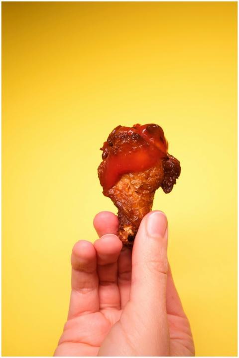 Hand holding delicious fried chicken drumstick wit