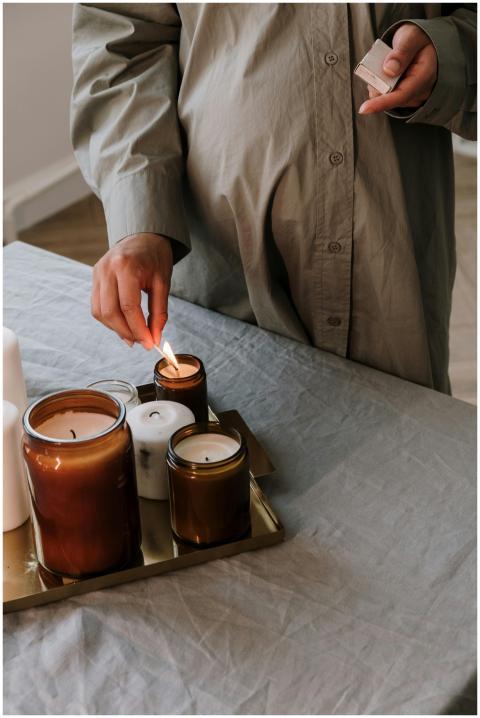 A pregnant woman gently lights candles on a tray,