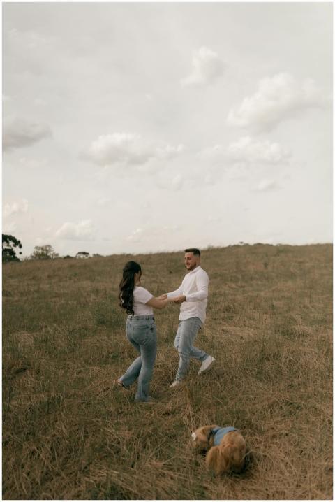 A couple dances joyfully in a grassy field with a
