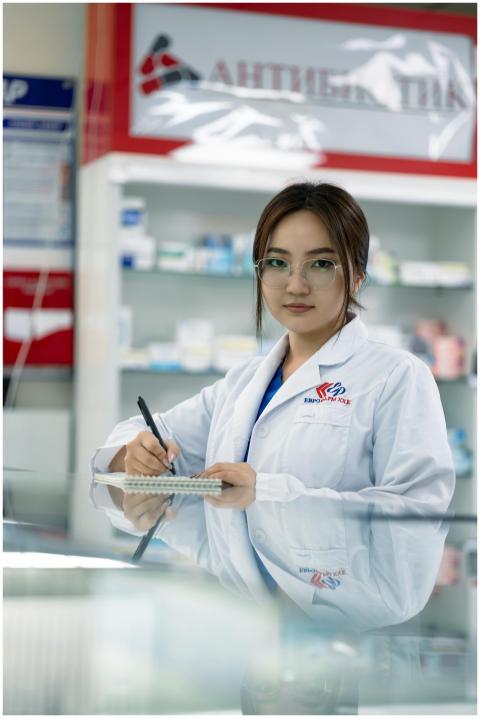 Female pharmacist writing in notepad inside a phar