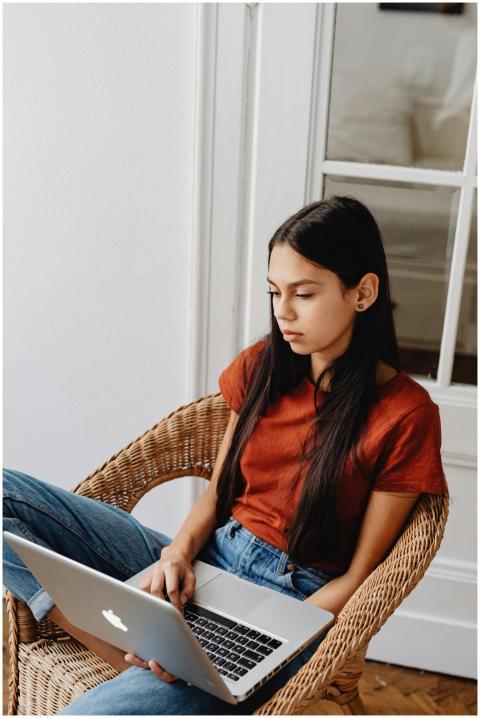 Young girl comfortably sitting indoors, focused on