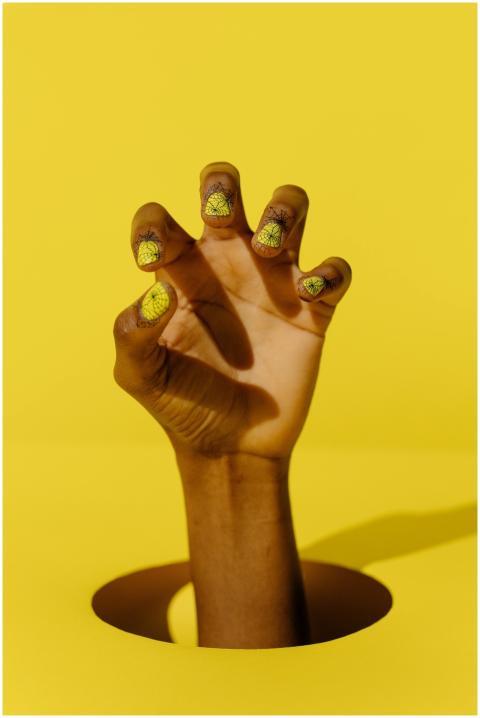 A creatively styled hand with yellow cracked nail