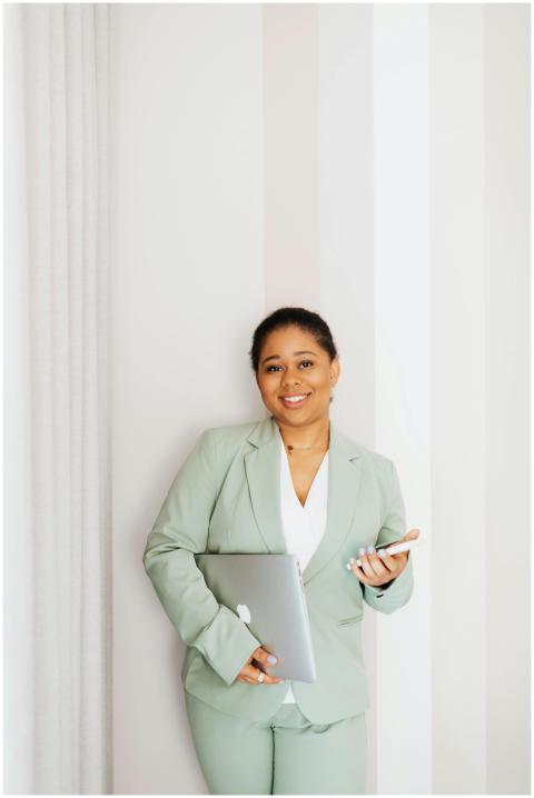 Smiling woman in business attire holding laptop an