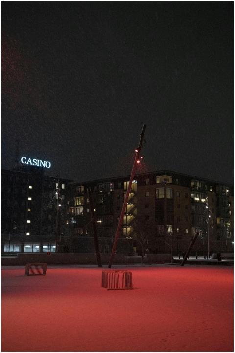 Red-lit snow scene at night with casino in the bac