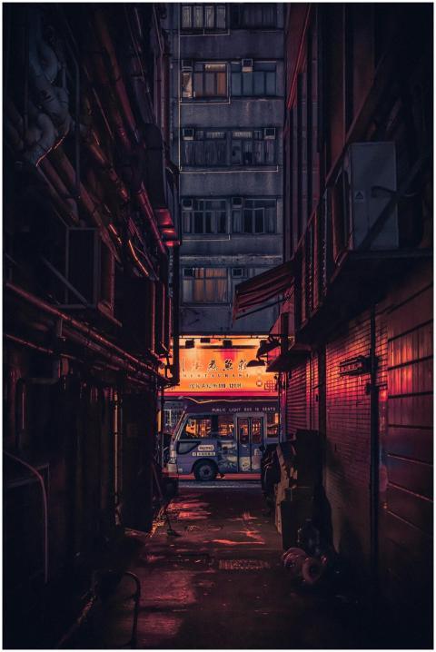 A dark alley in Hong Kong at night, illuminated by