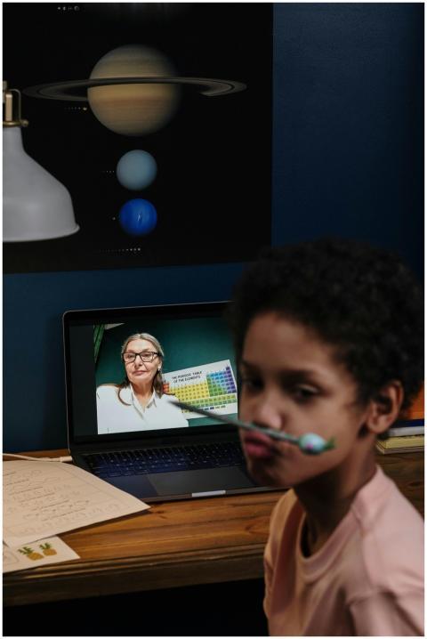 Child engaged in an online class with a teacher on