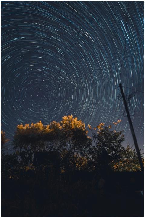 Captivating star trails swirl over a silhouette of