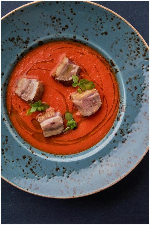 A gourmet dish featuring pork belly atop a rich re