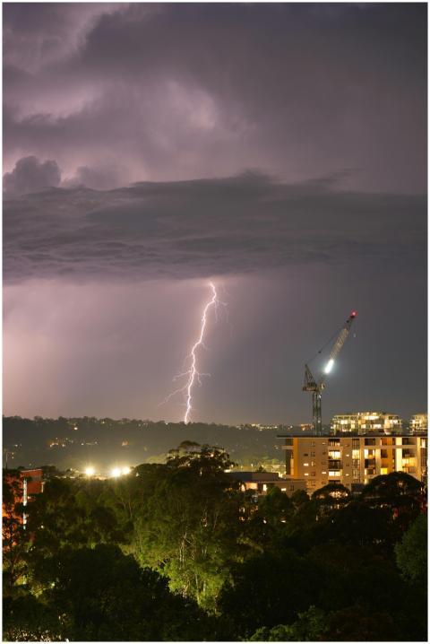 Striking lightning bolt over city skyline at night