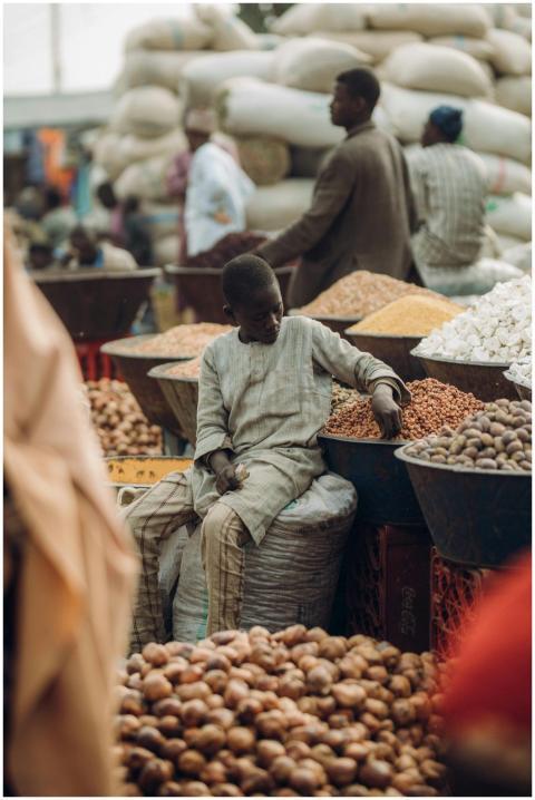 A young boy sits amidst a bustling market surround