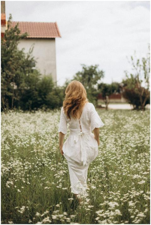 Back view of a woman in a white dress walking thro