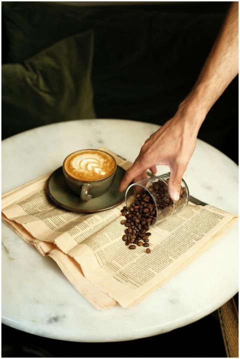 A hand reaches for spilled coffee beans next to a