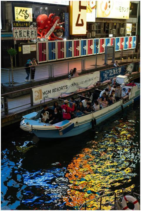 Vibrant canal boat ride with tourists in Dotonbori