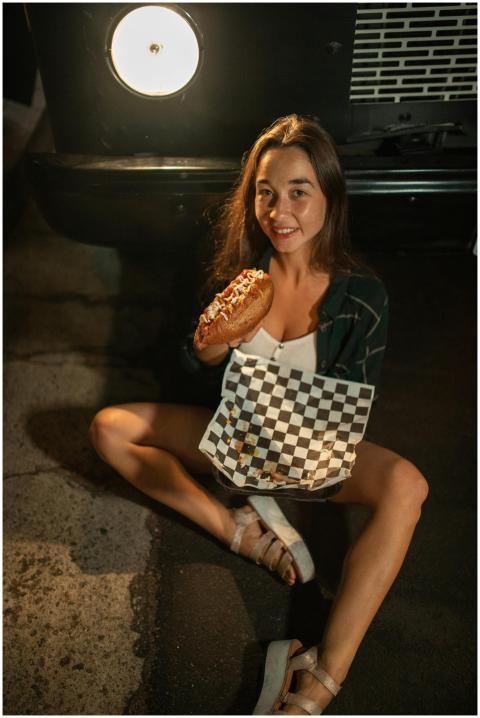 Young woman sitting near a food truck holding a ho