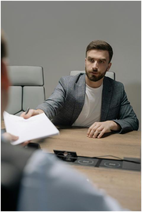 A man in a blazer negotiating across a table in a