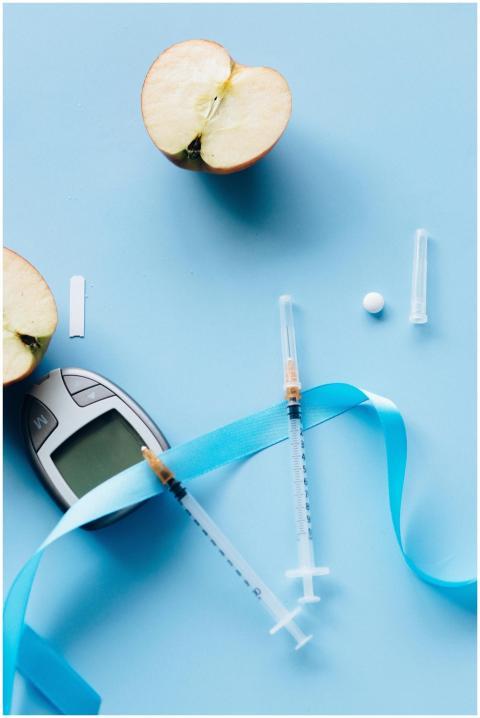 Flat lay of diabetes tools with sliced apple on bl