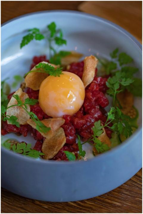 Delicious beef tartare topped with egg yolk and fr