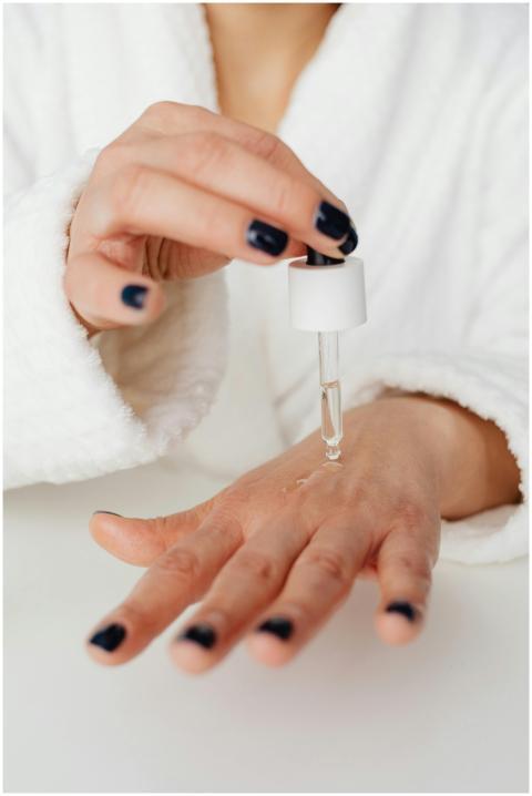 A close-up of a hand applying skincare serum with