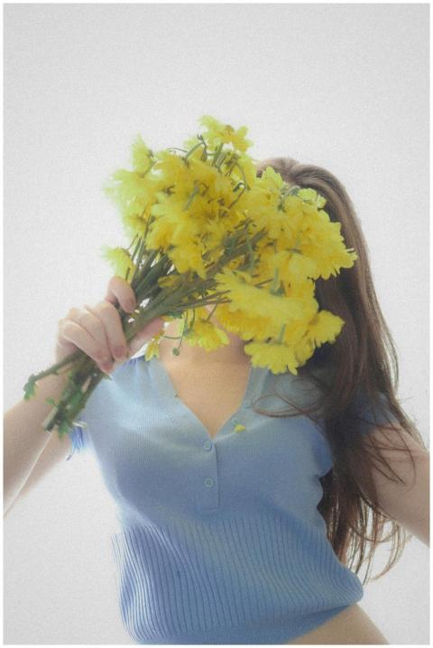 Woman in a blue shirt holding a bouquet of yellow
