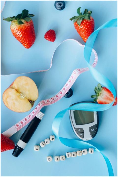 Fruits, glucose meter, and ribbon on a blue backgr