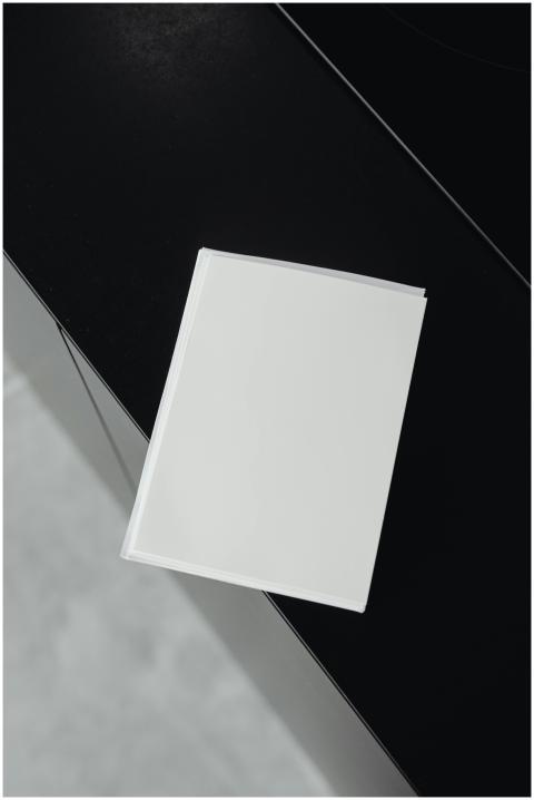 A blank white book on a sleek black surface, offer