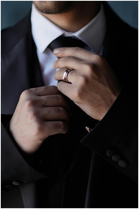 Sophisticated man adjusts necktie with ring, showc