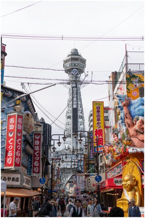 Lively street view in Osaka featuring Tsutenkaku T