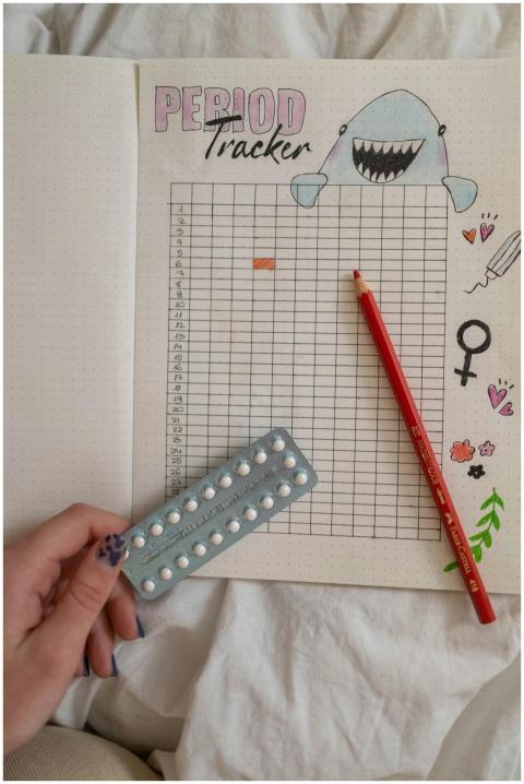 Creative period tracker notebook with a hand holdi
