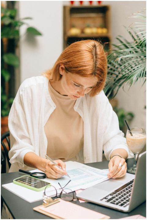 Woman analyzing financial documents using laptop a